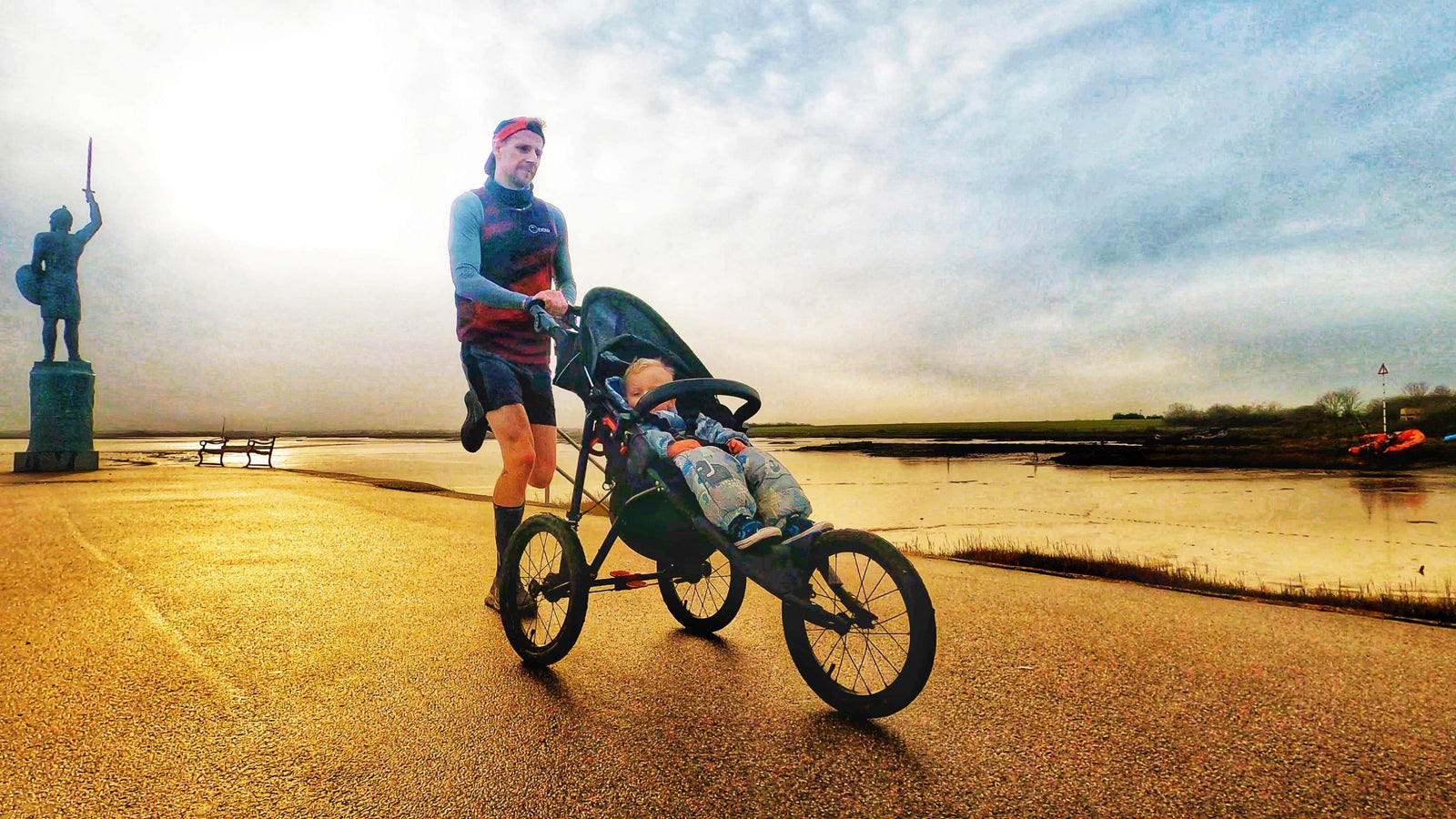 Man running outdoors with child in Nipper Sport pushchair